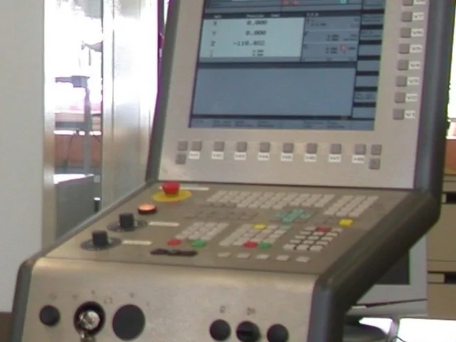 Szakember a CNC-vezérlő panelnél NC-programot tölt fel és ellenőriz